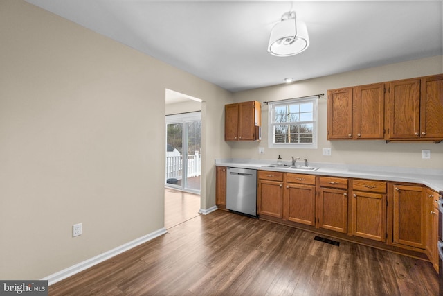 kitchen featuring brown cabinets, light countertops, dark wood finished floors, and stainless steel dishwasher