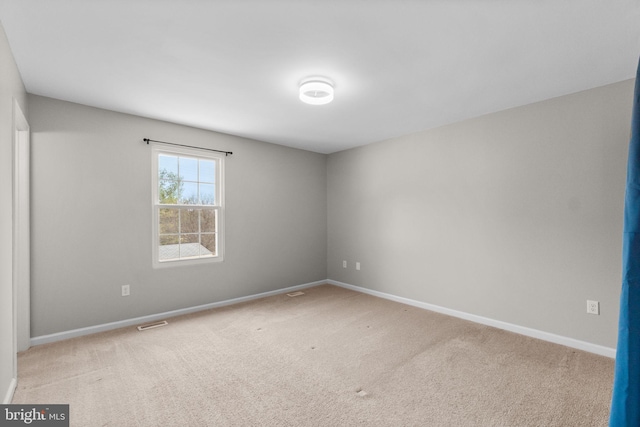 unfurnished room with light carpet, visible vents, and baseboards