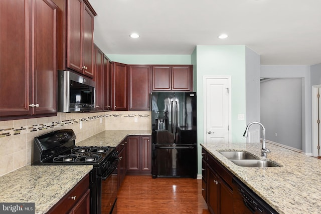 kitchen with light stone countertops, sink, dark hardwood / wood-style flooring, decorative backsplash, and black appliances