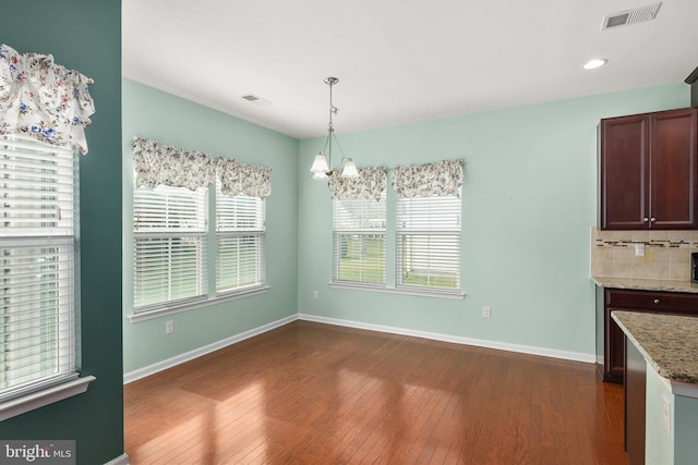 unfurnished dining area with dark hardwood / wood-style flooring and a chandelier