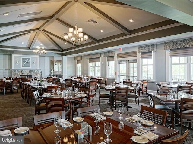 dining room with vaulted ceiling with beams, a fireplace, and a chandelier