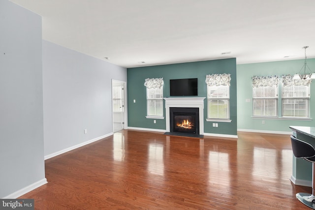 unfurnished living room featuring a chandelier and wood-type flooring