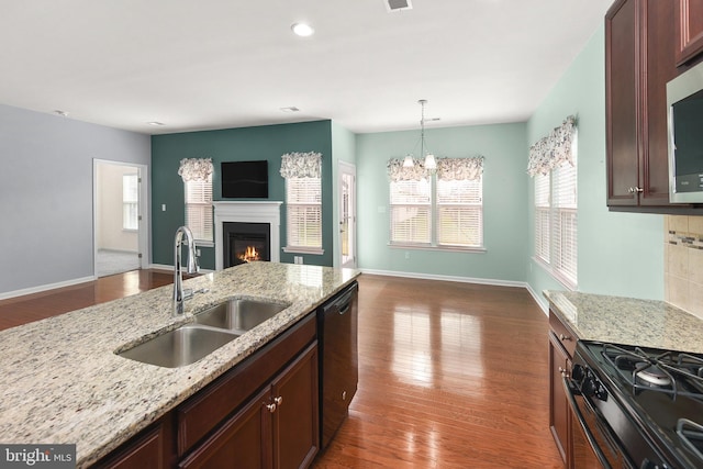 kitchen featuring light stone counters, black appliances, sink, decorative light fixtures, and a chandelier