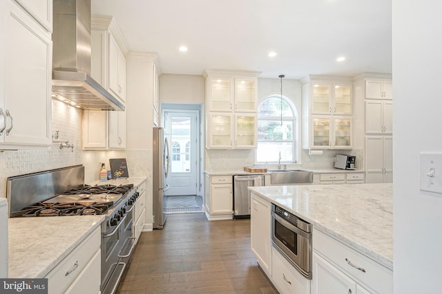 kitchen with white cabinetry, sink, wall chimney exhaust hood, pendant lighting, and appliances with stainless steel finishes