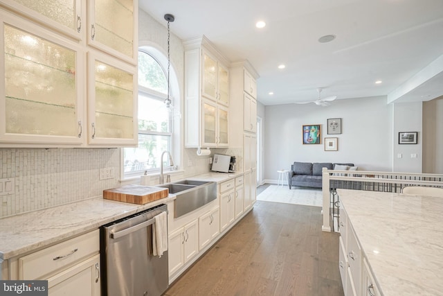 kitchen featuring light stone countertops, sink, dishwasher, light hardwood / wood-style floors, and hanging light fixtures