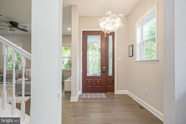 entrance foyer with ceiling fan with notable chandelier and wood-type flooring