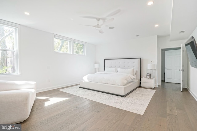 bedroom featuring hardwood / wood-style floors, ceiling fan, and multiple windows