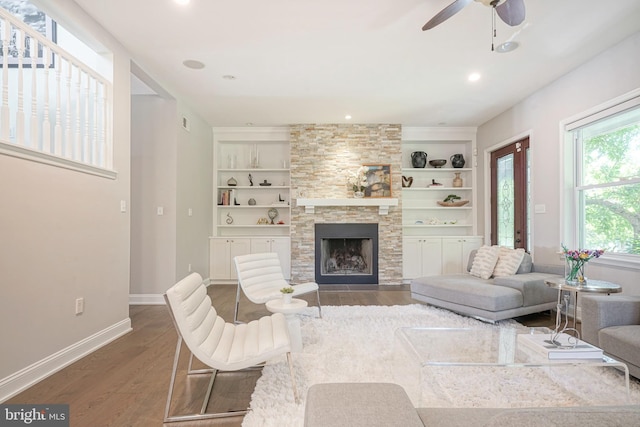 living room featuring built in features, a fireplace, and dark wood-type flooring