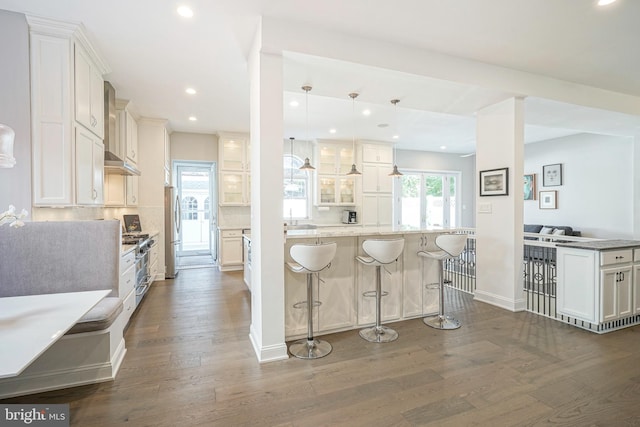 kitchen featuring white cabinetry, hanging light fixtures, dark hardwood / wood-style floors, a kitchen bar, and appliances with stainless steel finishes