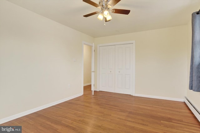 unfurnished bedroom featuring hardwood / wood-style floors, a closet, a baseboard radiator, and ceiling fan