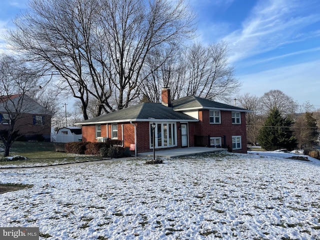 snow covered back of property featuring a patio area