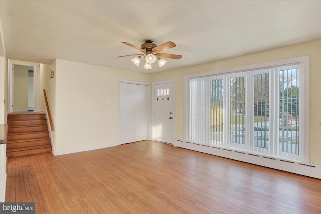 interior space with light wood-type flooring, baseboard heating, and ceiling fan