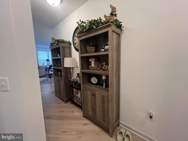 corridor with vaulted ceiling and light hardwood / wood-style flooring