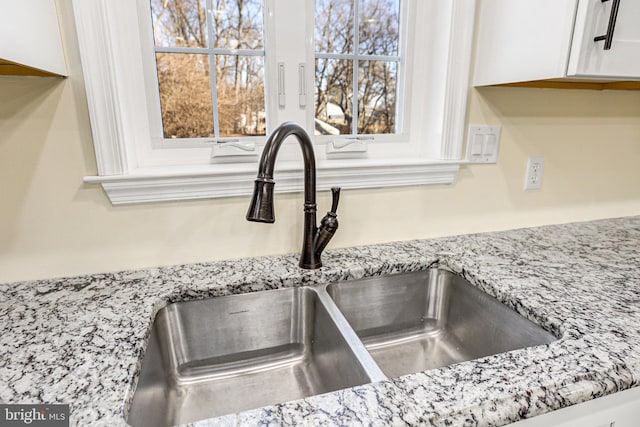 room details featuring light stone countertops, white cabinetry, and sink