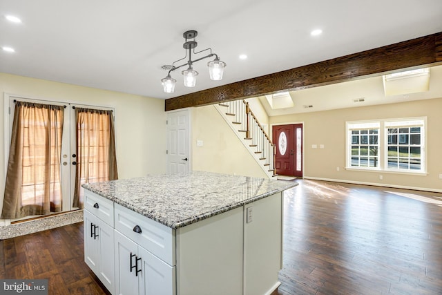 kitchen with white cabinetry, beamed ceiling, decorative light fixtures, and a kitchen island