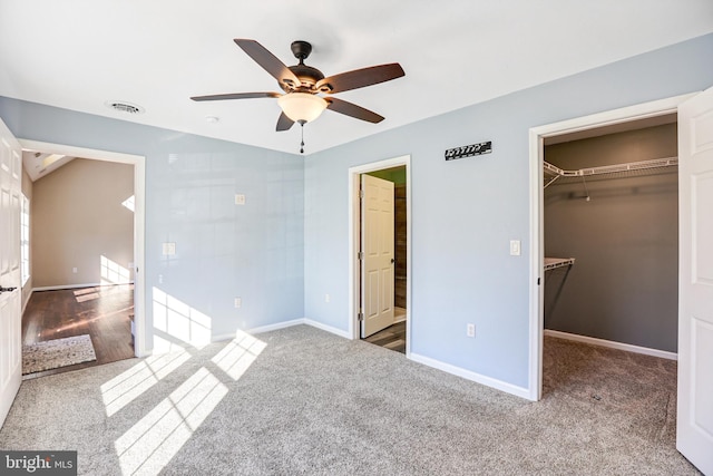 unfurnished bedroom with carpet, ensuite bath, ceiling fan, a spacious closet, and a closet