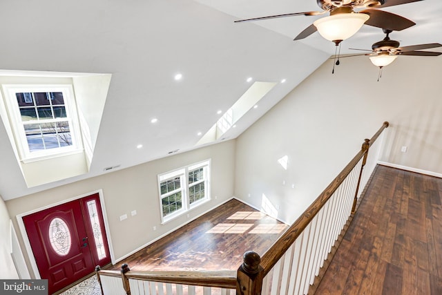 foyer entrance featuring a skylight, ceiling fan, high vaulted ceiling, and dark wood-type flooring