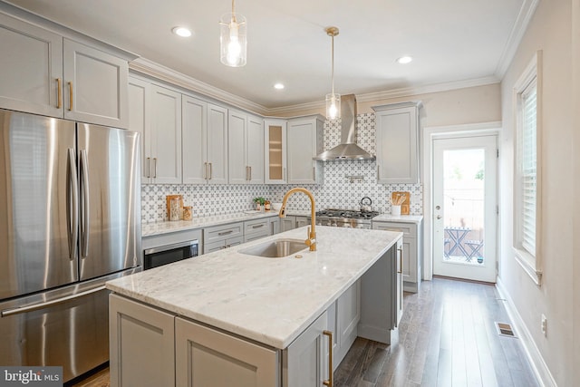 kitchen with appliances with stainless steel finishes, light stone countertops, hanging light fixtures, and wall chimney range hood