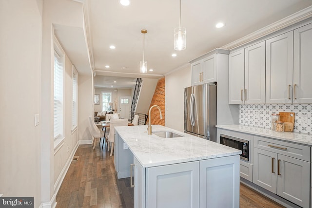 kitchen with built in microwave, hanging light fixtures, stainless steel fridge, gray cabinets, and an island with sink