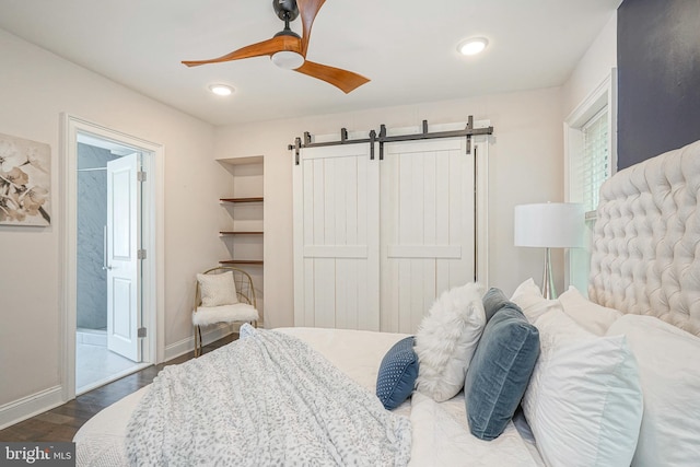 bedroom featuring ensuite bath, dark hardwood / wood-style floors, a closet, ceiling fan, and a barn door