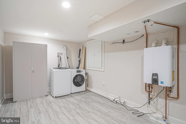 laundry room featuring water heater, washing machine and clothes dryer, and light wood-type flooring