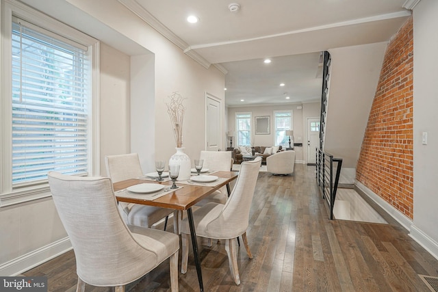 dining room featuring ornamental molding, brick wall, and dark hardwood / wood-style floors