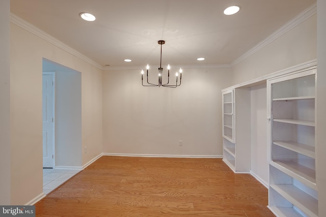 unfurnished dining area featuring a chandelier, light hardwood / wood-style floors, and crown molding