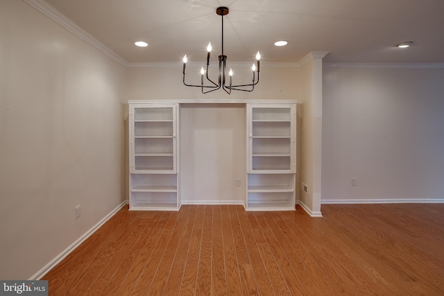 unfurnished dining area featuring hardwood / wood-style flooring, ornamental molding, and an inviting chandelier