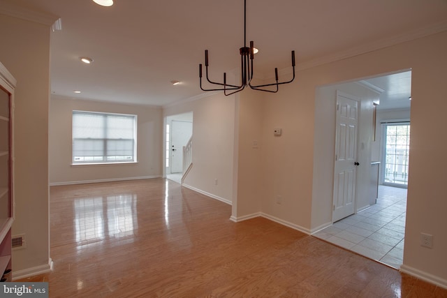 unfurnished dining area featuring light hardwood / wood-style flooring, crown molding, and a notable chandelier