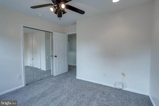 unfurnished bedroom with dark colored carpet, a closet, and ceiling fan