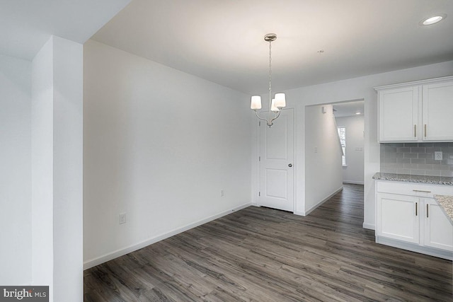 unfurnished dining area with dark hardwood / wood-style flooring and an inviting chandelier