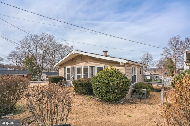 view of home's exterior featuring a chimney and fence