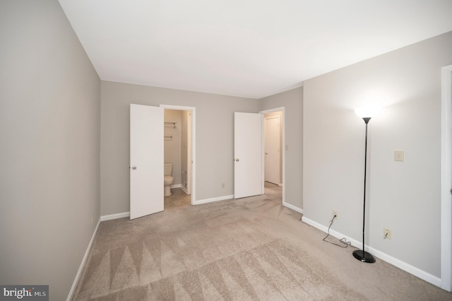 unfurnished bedroom with light carpet and connected bathroom