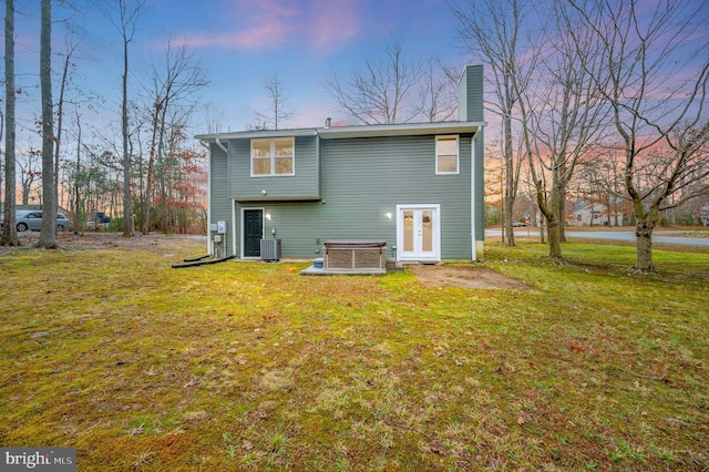 back house at dusk with central AC unit and a yard