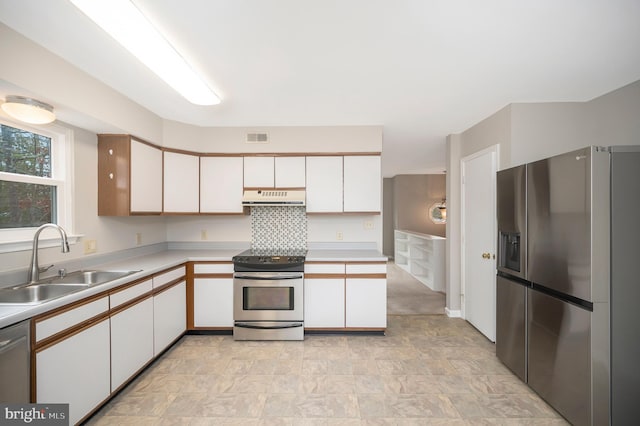 kitchen featuring backsplash, sink, white cabinets, and appliances with stainless steel finishes