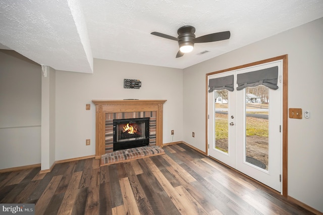 unfurnished living room featuring a textured ceiling, ceiling fan, dark hardwood / wood-style floors, and a brick fireplace