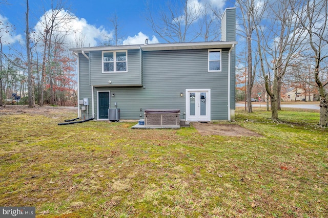 rear view of property featuring central air condition unit, a lawn, and french doors