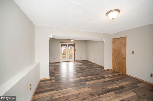 spare room with a textured ceiling, french doors, and dark hardwood / wood-style floors