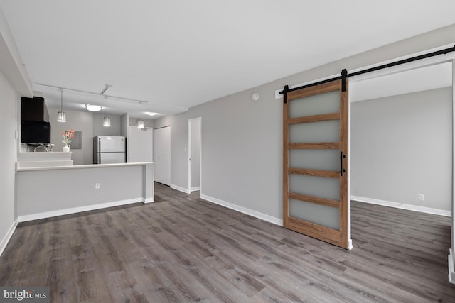 unfurnished living room with a barn door and wood-type flooring