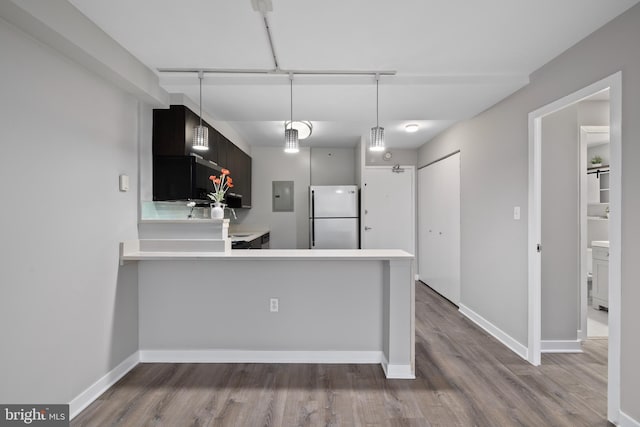 kitchen with kitchen peninsula, wood-type flooring, white refrigerator, and electric panel