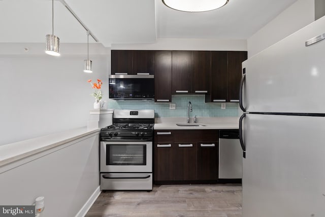 kitchen featuring sink, stainless steel appliances, light hardwood / wood-style flooring, backsplash, and decorative light fixtures