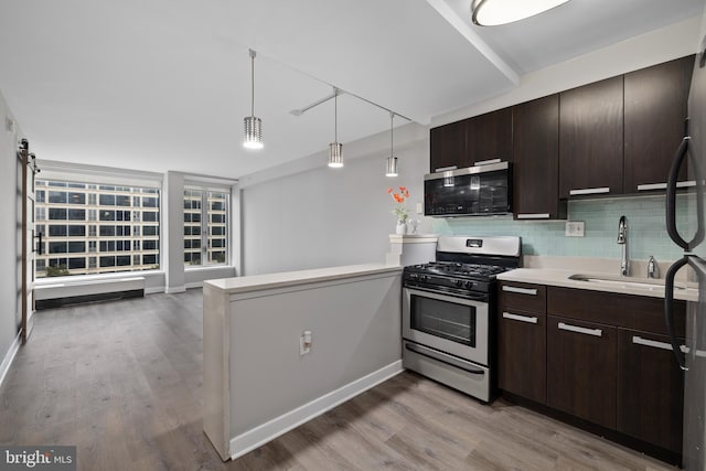 kitchen featuring decorative backsplash, kitchen peninsula, gas stove, sink, and pendant lighting