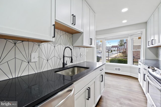 kitchen with sink, tasteful backsplash, light hardwood / wood-style floors, white cabinetry, and stainless steel appliances