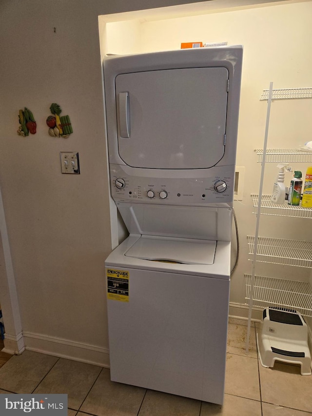 clothes washing area featuring light tile patterned floors and stacked washer / dryer