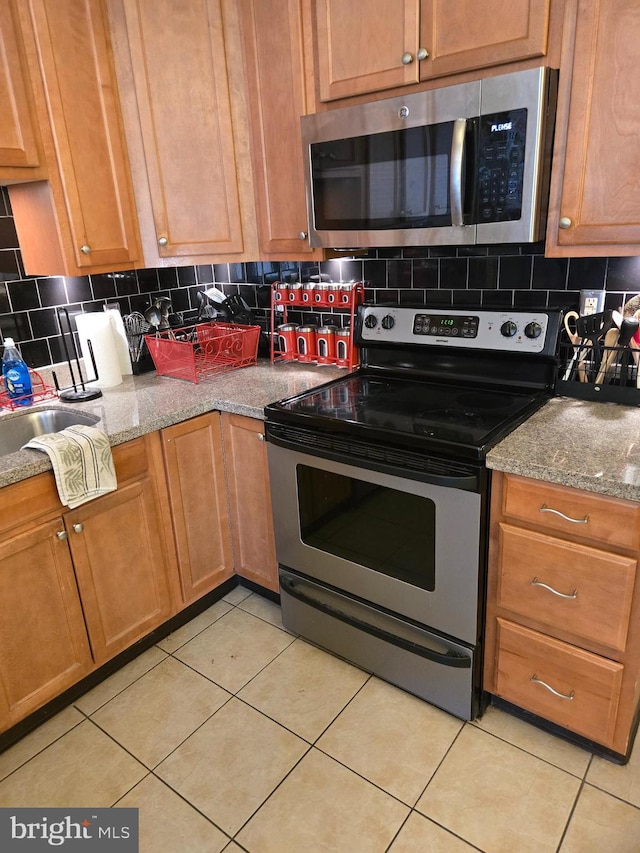 kitchen featuring light stone counters, light tile patterned floors, backsplash, and appliances with stainless steel finishes