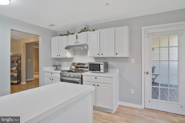 kitchen featuring stainless steel gas stove, white cabinets, and light hardwood / wood-style floors