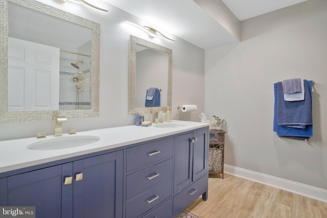 bathroom featuring a tile shower, vanity, and wood-type flooring