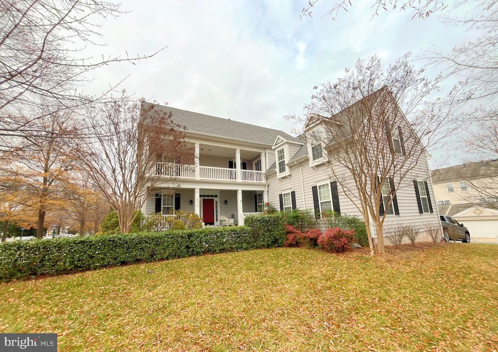 view of front of house featuring covered porch, a balcony, and a front yard