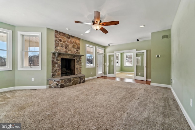 unfurnished living room featuring a wealth of natural light, ceiling fan, a fireplace, and carpet