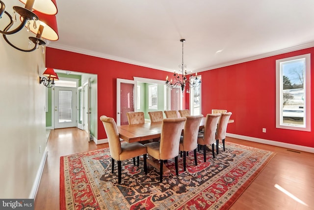 dining area with crown molding, hardwood / wood-style floors, and an inviting chandelier